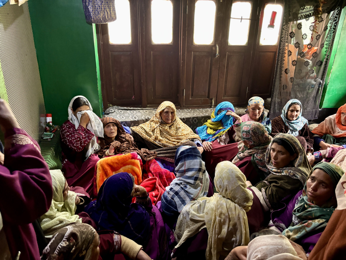 A young woman wipes tears with her headscarf while cradling Ahmad’s mother in her left arm.