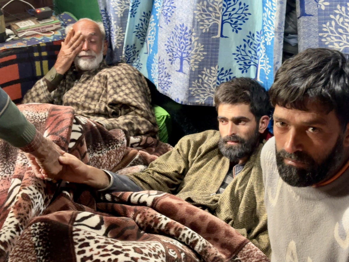 Ahmad’s father, flanked by his two other sons, wipes tears from his eyes at their home.